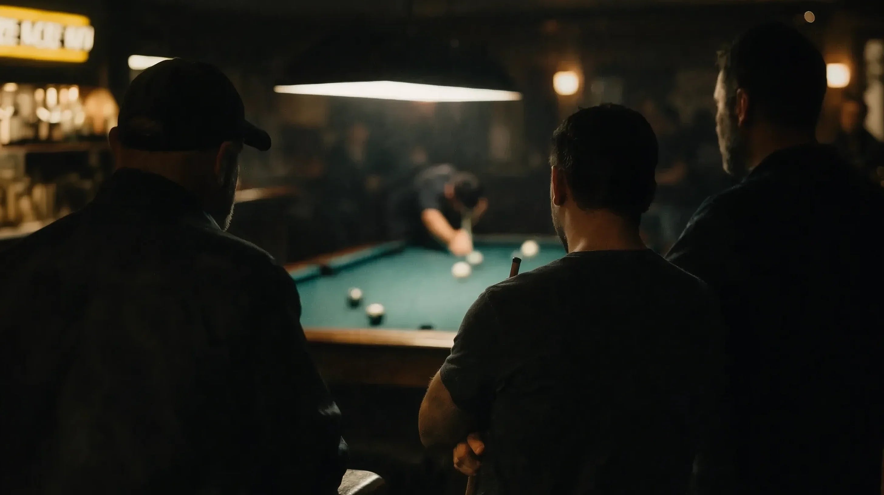 Men in foreground watching a pool player shooting at table