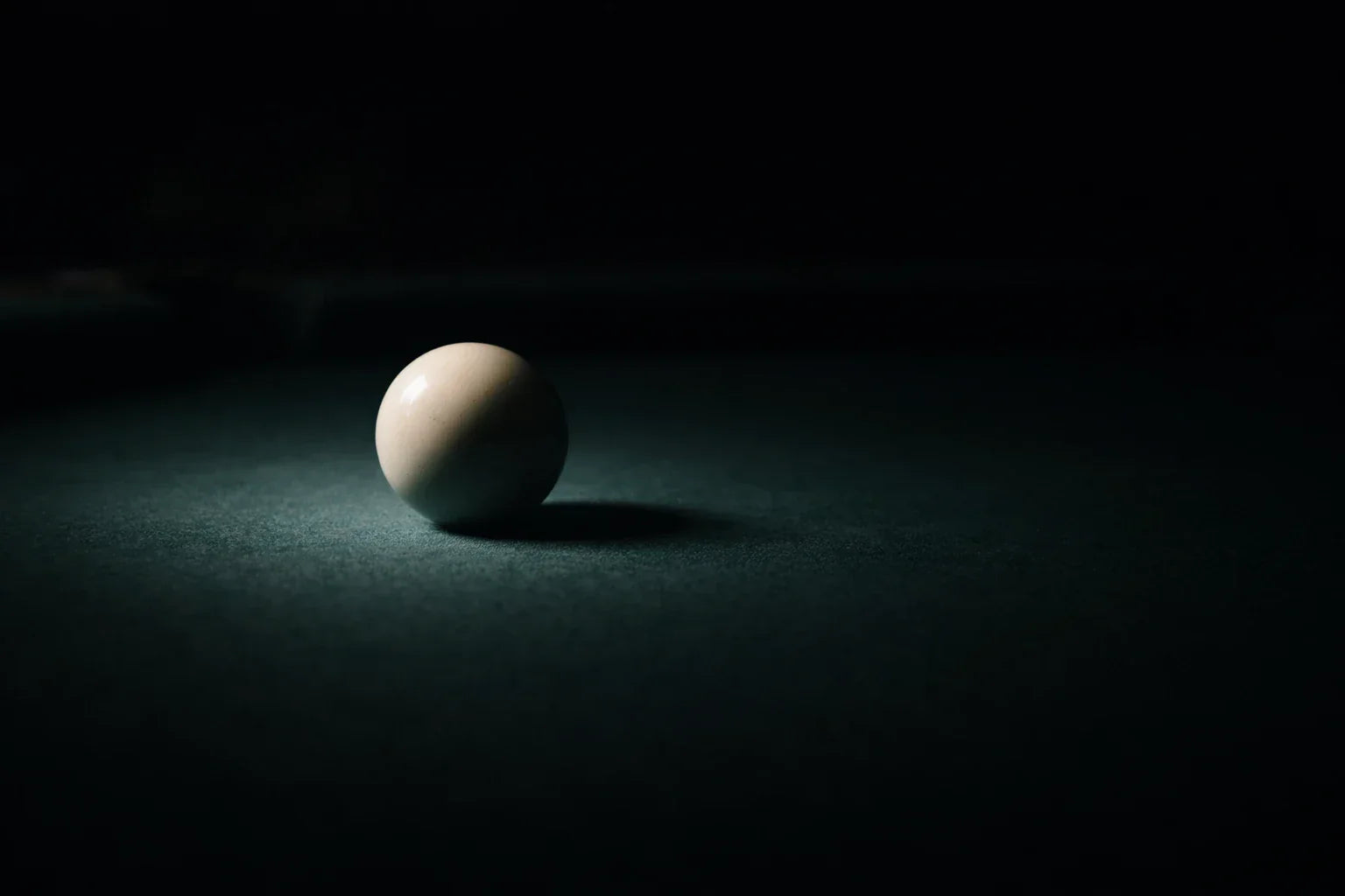 A lone cue ball on a green table with dramatic lighting